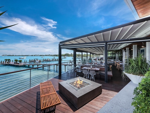 deck with an outdoor fire pit, a water view, and a boat dock