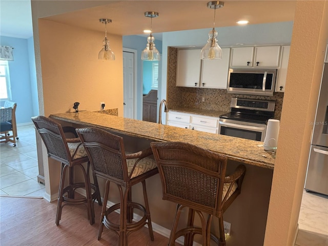 40 Mariner Ln, Rotonda West, FL 33947 - kitchen with appliances with stainless steel finishes, tasteful backsplash, white cabinetry, light stone counters, and baseboards