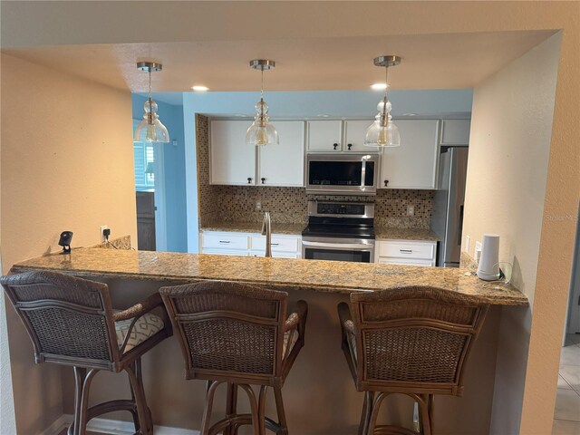 40 Mariner Ln, Rotonda West, FL 33947 - kitchen featuring stainless steel appliances, decorative backsplash, white cabinetry, and a peninsula