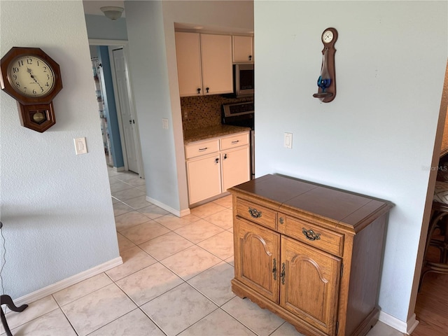 40 Mariner Ln, Rotonda West, FL 33947 - kitchen with stainless steel microwave, light tile patterned flooring, baseboards, decorative backsplash, and tile counters