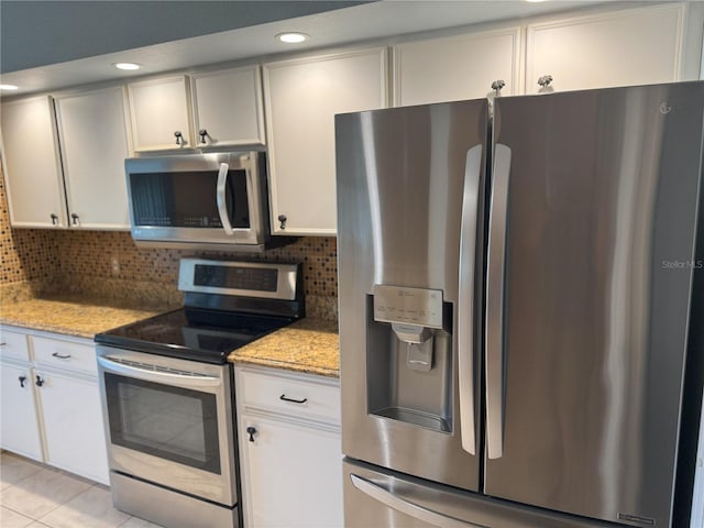 40 Mariner Ln, Rotonda West, FL 33947 - kitchen with stainless steel appliances, backsplash, light tile patterned flooring, light stone countertops, and recessed lighting