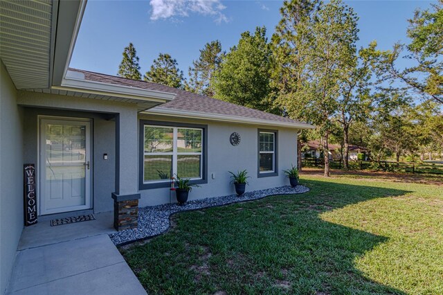 9085 SW 202nd Avenue Rd, Dunnellon, FL 34431 - property entrance with stucco siding, a yard, and a shingled roof