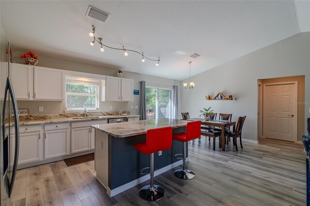 9085 SW 202nd Avenue Rd, Dunnellon, FL 34431 - kitchen featuring white cabinets, a chandelier, light wood-style flooring, appliances with stainless steel finishes, and lofted ceiling