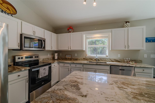 9085 SW 202nd Avenue Rd, Dunnellon, FL 34431 - kitchen with stainless steel appliances, a sink, light stone countertops, white cabinets, and lofted ceiling