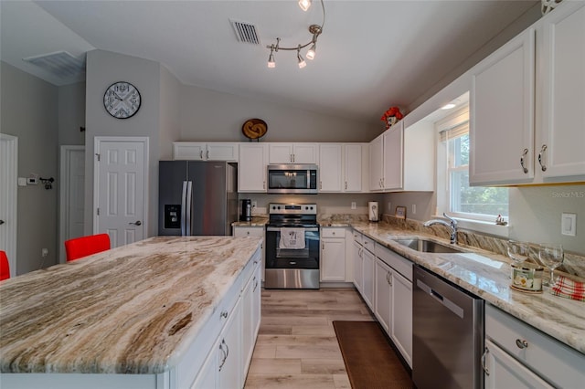 9085 SW 202nd Avenue Rd, Dunnellon, FL 34431 - kitchen with stainless steel appliances, vaulted ceiling, a sink, light stone countertops, and light wood finished floors