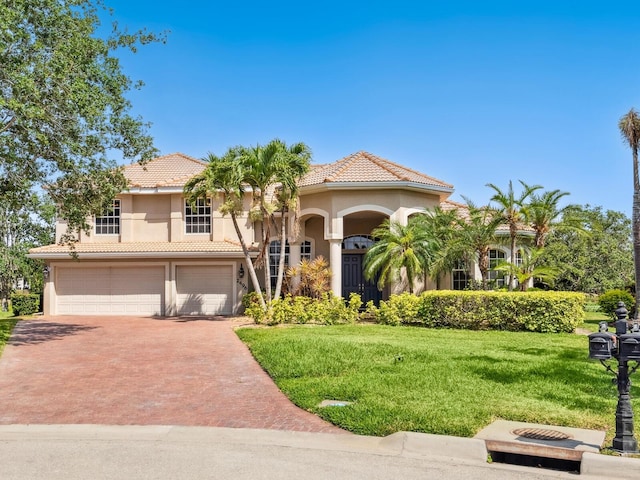 mediterranean / spanish house featuring a tile roof, driveway, stucco siding, and a front yard