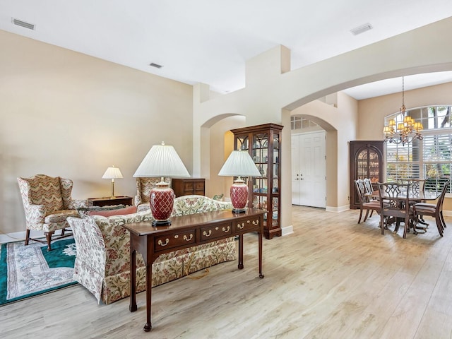 living room with arched walkways, a chandelier, wood finished floors, and baseboards