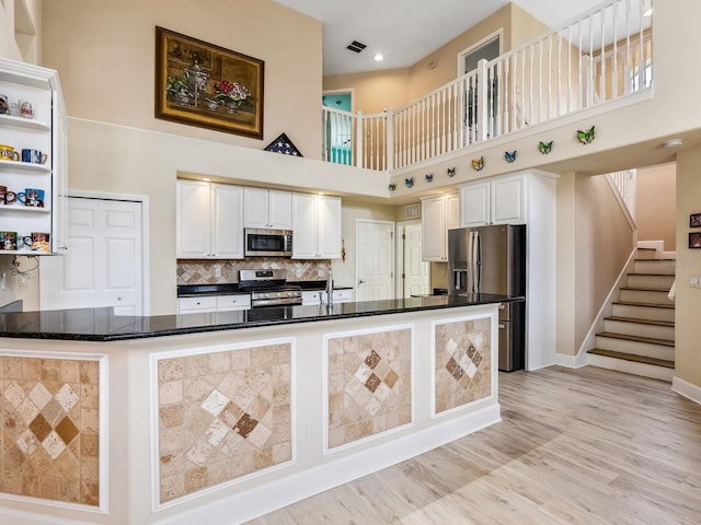kitchen with appliances with stainless steel finishes, a high ceiling, white cabinetry, open shelves, and baseboards