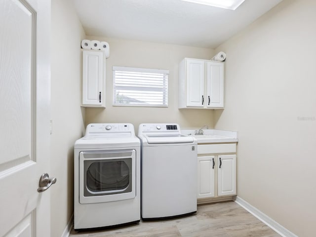 clothes washing area featuring separate washer and dryer, cabinet space, light wood finished floors, and baseboards