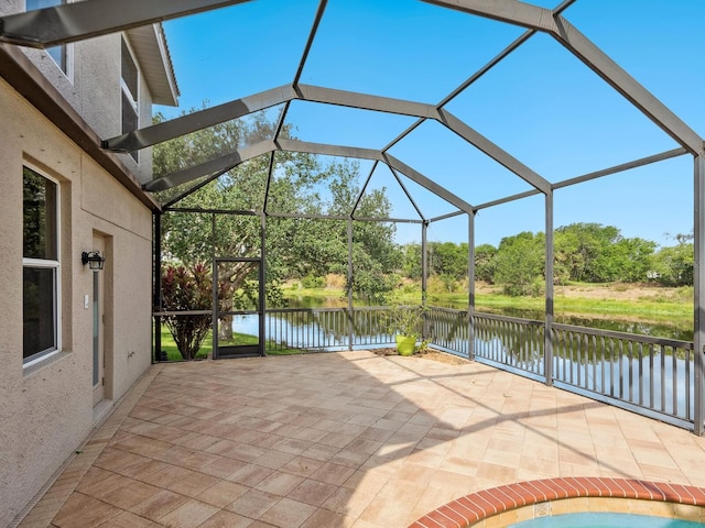 view of patio with a water view, a lanai, and view of scattered trees