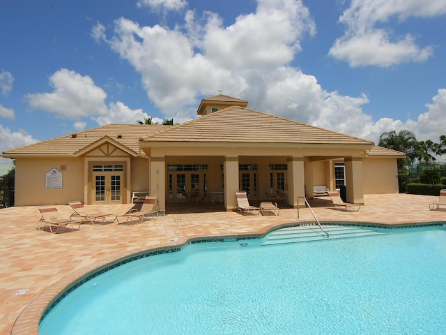community pool with french doors and a patio area