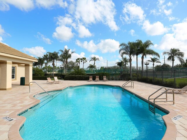 community pool with a patio area and fence