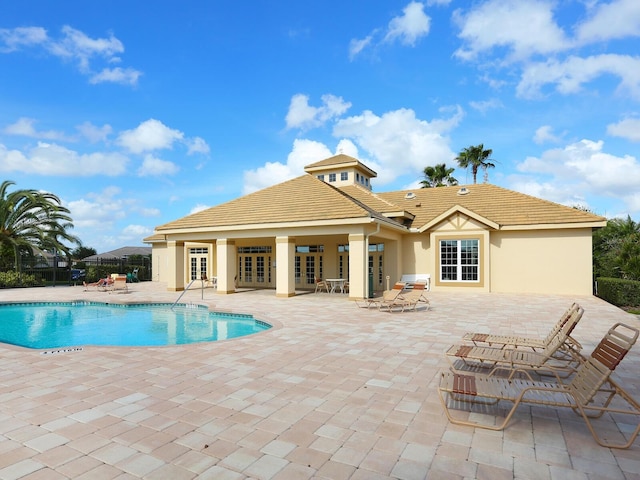community pool with french doors, a patio area, and fence