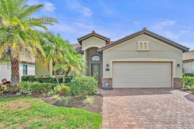 view of front of house with stucco siding, decorative driveway, an attached garage, and a tiled roof
