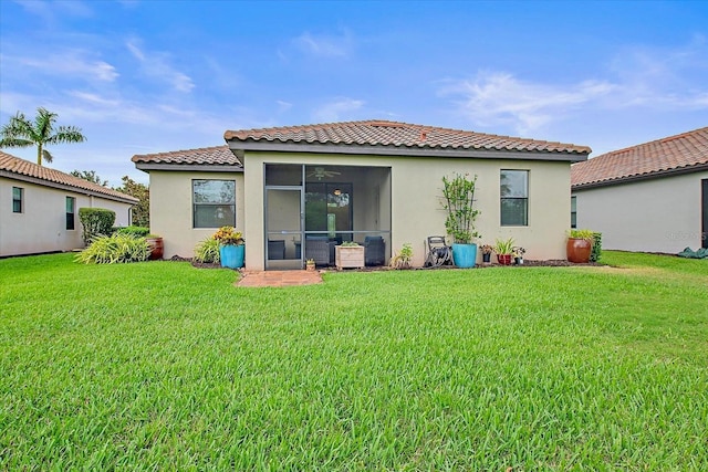 rear view of house with stucco siding, a sunroom, a lawn, and a tiled roof