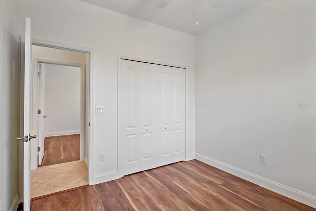 unfurnished bedroom featuring wood finished floors, baseboards, and a closet