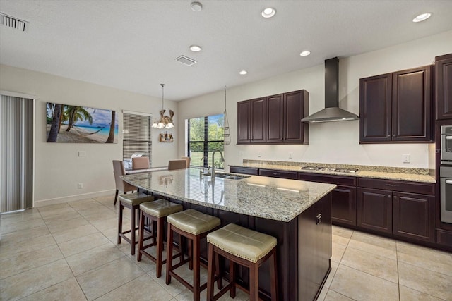 9769 Highland Park Pl, Palmetto, FL 34221 - kitchen featuring a sink, wall chimney exhaust hood, stainless steel gas cooktop, a kitchen bar, and light tile patterned floors