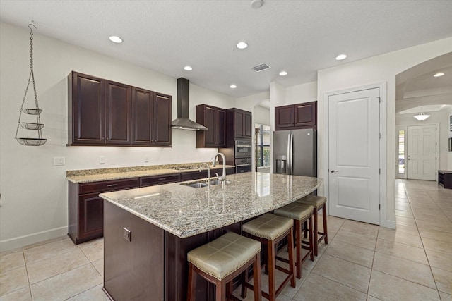 9769 Highland Park Pl, Palmetto, FL 34221 - kitchen with wall chimney range hood, arched walkways, stainless steel appliances, a sink, and a breakfast bar