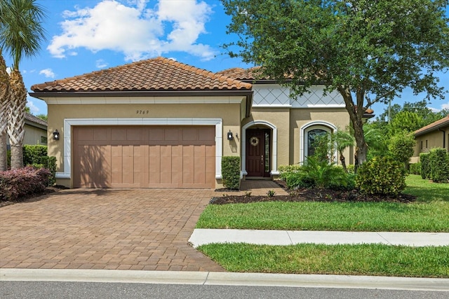 9769 Highland Park Pl, Palmetto, FL 34221 - mediterranean / spanish home with stucco siding, a garage, decorative driveway, and a tiled roof