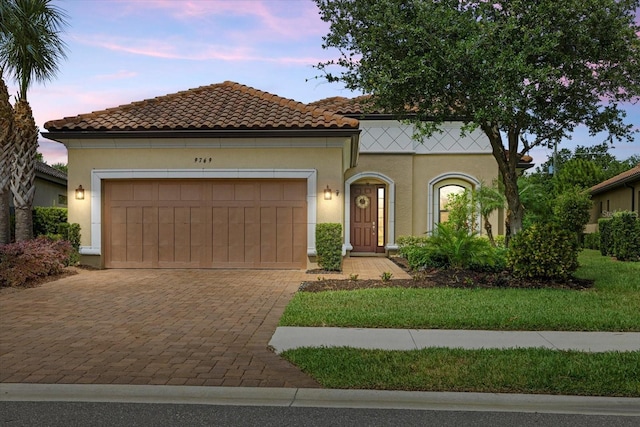 9769 Highland Park Pl, Palmetto, FL 34221 - mediterranean / spanish home featuring stucco siding, an attached garage, driveway, and a tiled roof