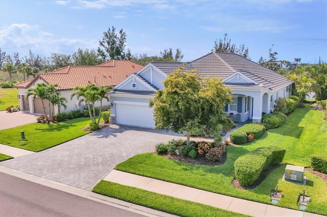 view of front facade with decorative driveway, stucco siding, a front lawn, a garage, and a tile roof