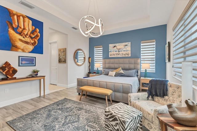 bedroom featuring a chandelier, a raised ceiling, wood finished floors, and baseboards