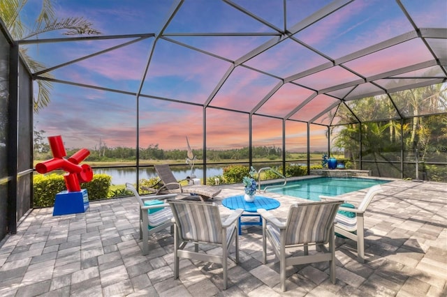 pool at dusk with a water view, a patio, an outdoor pool, and glass enclosure