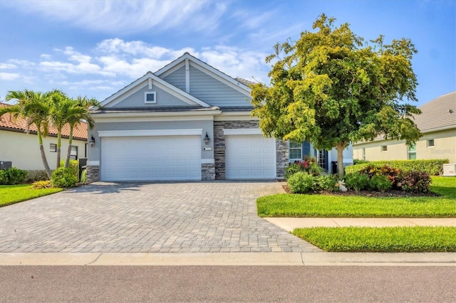 view of front facade with decorative driveway, stone siding, a garage, and stucco siding