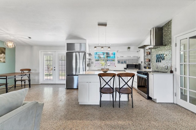 6931 Magellan Way, Sarasota, FL 34243 - kitchen featuring appliances with stainless steel finishes, wall chimney exhaust hood, dark aggregate flooring, white cabinetry, and hanging light fixtures