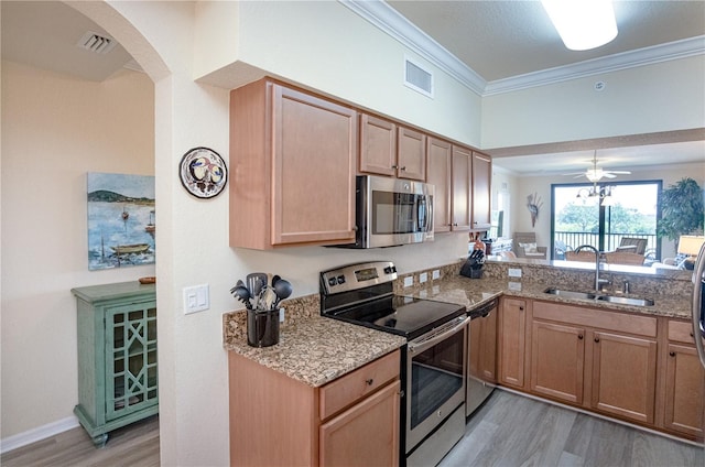 7005 River Hammock Dr Unit 204, Bradenton, FL 34212 - kitchen featuring appliances with stainless steel finishes, a sink, light wood-type flooring, crown molding, and arched walkways