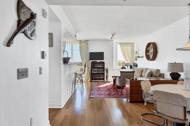 living area with plenty of natural light, hardwood / wood-style floors, and baseboards