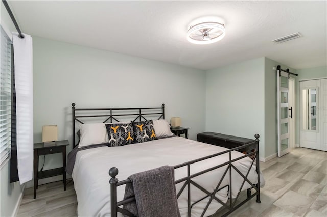 6999 W Country Club Dr N Unit 224, Sarasota, FL 34243 - bedroom featuring a barn door, baseboards, and light wood-type flooring