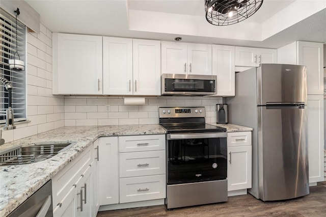104 Capri Isles Blvd Unit 207, Venice, FL 34292 - kitchen featuring stainless steel appliances, dark wood-style floors, a raised ceiling, white cabinetry, and tasteful backsplash