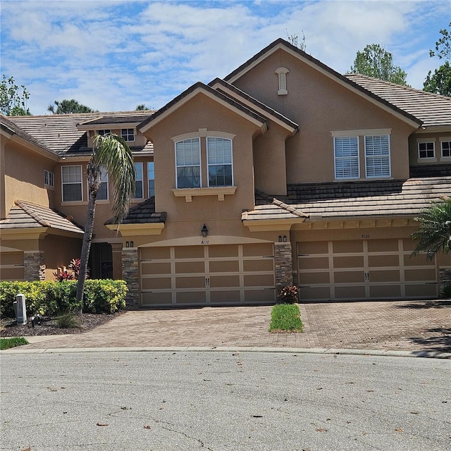 8110 Villa Grande Ct, Sarasota, FL 34243 - townhome / multi-family property with an attached garage, stone siding, and stucco siding