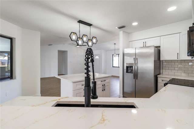 3239 Daytona Dr, Punta Gorda, FL 33983 - kitchen featuring stainless steel fridge, light stone counters, decorative light fixtures, white cabinets, and backsplash