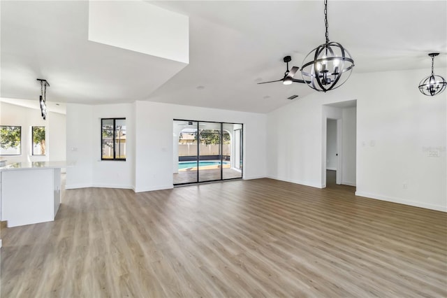 3239 Daytona Dr, Punta Gorda, FL 33983 - unfurnished living room featuring a chandelier, lofted ceiling, light wood-style flooring, and baseboards