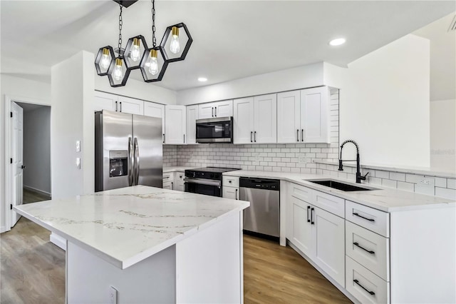 3239 Daytona Dr, Punta Gorda, FL 33983 - kitchen with appliances with stainless steel finishes, a sink, a center island, light wood finished floors, and light stone counters