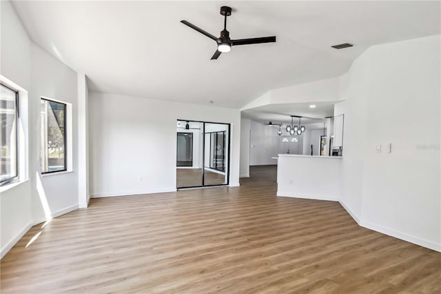 3239 Daytona Dr, Punta Gorda, FL 33983 - unfurnished living room with light wood-style floors, ceiling fan, lofted ceiling, a chandelier, and baseboards