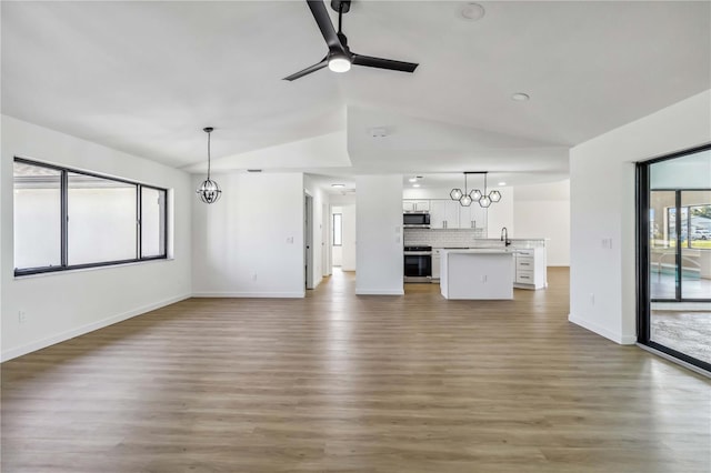 3239 Daytona Dr, Punta Gorda, FL 33983 - unfurnished living room with vaulted ceiling, a ceiling fan, wood finished floors, baseboards, and a chandelier