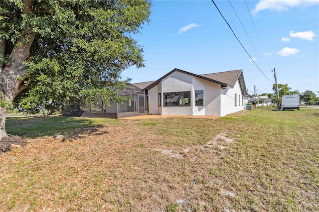 3239 Daytona Dr, Punta Gorda, FL 33983 - rear view of house with stucco siding, a lawn, glass enclosure, and central AC unit