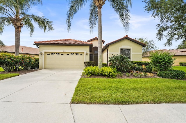 8118 Stirling Falls Cir, Sarasota, FL 34243 - mediterranean / spanish home with stucco siding, an attached garage, a front lawn, driveway, and a tile roof