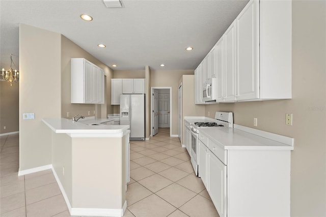 8118 Stirling Falls Cir, Sarasota, FL 34243 - kitchen featuring white appliances, a peninsula, light tile patterned floors, white cabinets, and recessed lighting