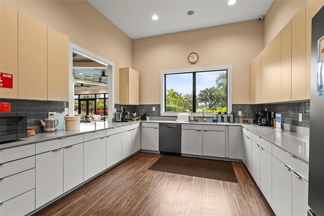8118 Stirling Falls Cir, Sarasota, FL 34243 - kitchen with stainless steel dishwasher, black microwave, dark wood-style floors, decorative backsplash, and light countertops