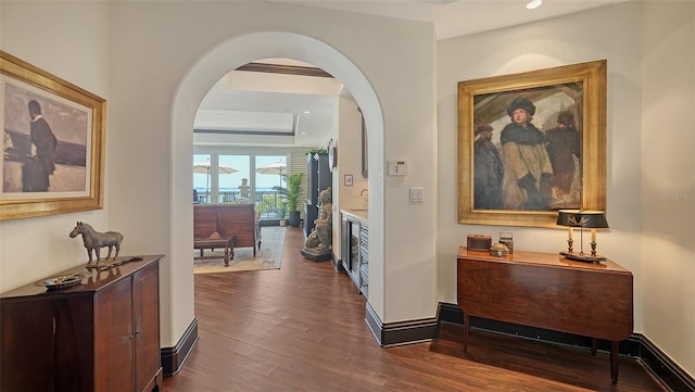 420 Golden Gate Pt Unit 200A, Sarasota, FL 34236 - hall with dark wood-style flooring, arched walkways, recessed lighting, a tray ceiling, and baseboards