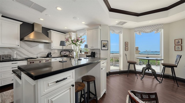 420 Golden Gate Pt Unit 200A, Sarasota, FL 34236 - kitchen with wall chimney range hood, ornamental molding, dark countertops, healthy amount of natural light, and dark wood finished floors