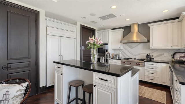 420 Golden Gate Pt Unit 200A, Sarasota, FL 34236 - kitchen featuring wall chimney range hood, dark countertops, dark wood finished floors, stainless steel gas stovetop, and recessed lighting