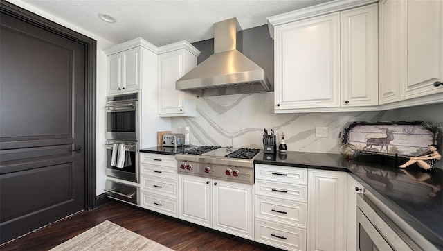 420 Golden Gate Pt Unit 200A, Sarasota, FL 34236 - kitchen featuring wall chimney exhaust hood, stainless steel appliances, a warming drawer, dark countertops, and dark wood-style floors