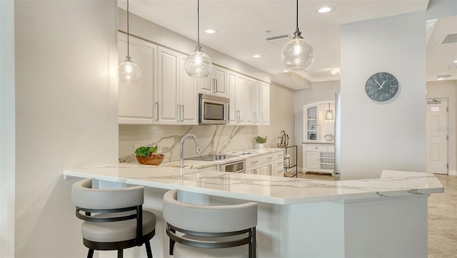 606 Riviera Dunes Way Unit 306, Palmetto, FL 34221 - kitchen with stainless steel microwave, light stone counters, recessed lighting, a breakfast bar, and a peninsula