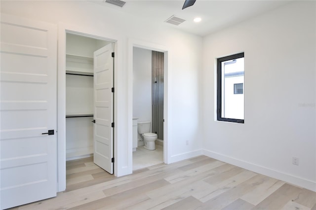 2335 Oak Ter, Sarasota, FL 34231 - unfurnished bedroom with a spacious closet, light wood finished floors, baseboards, a closet, and connected bathroom