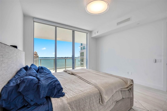 301 Quay Commons Unit 1711, Sarasota, FL 34236 - bedroom featuring floor to ceiling windows, access to outside, light wood-style flooring, and a water view
